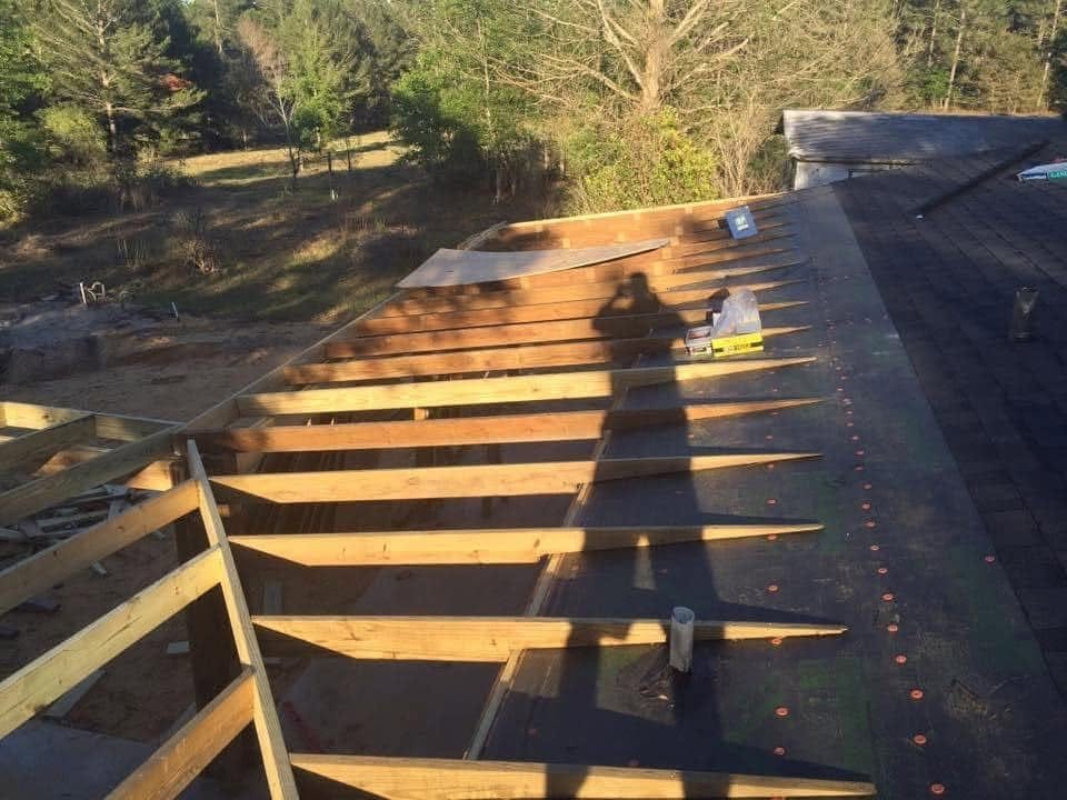 New wood rafters framed over a porch, tying into the existing roof